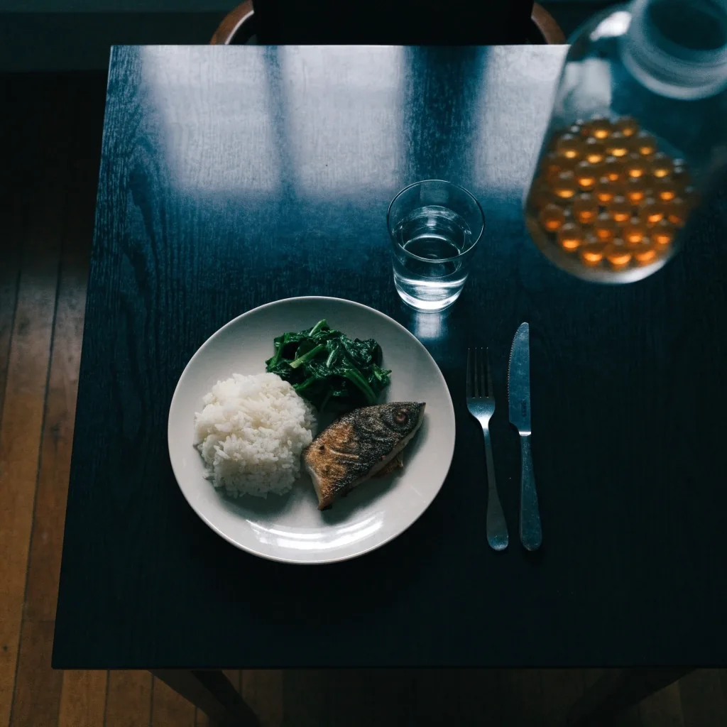 Overhead view of a simple home meal beside a glass of water and a supplement bottle